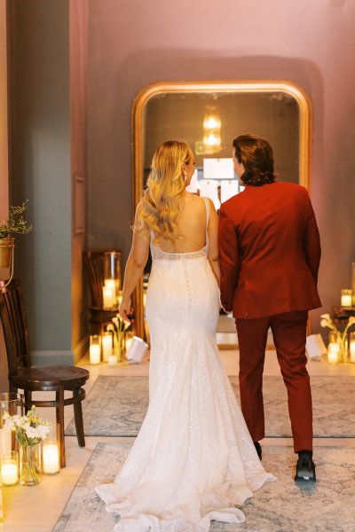 Groom in red suit bride interior candles lighting from behind