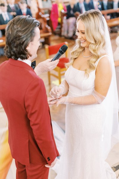 Groom and bride with guests behind them in church microphone vows