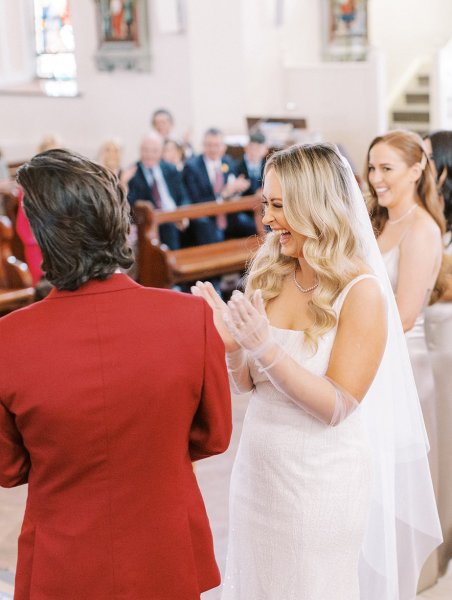 Bride and groom with guests in background laughing