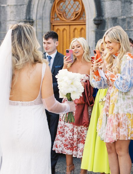 Bride holding flowers veil detail and guests