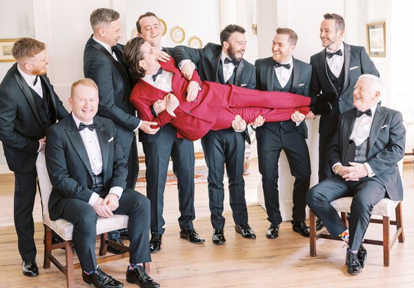 Groomsmen holding carrying groom suits red suit