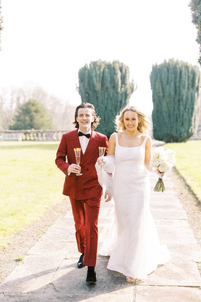 Bride and groom walking towards stately home manor wedding venue flowers and champagne