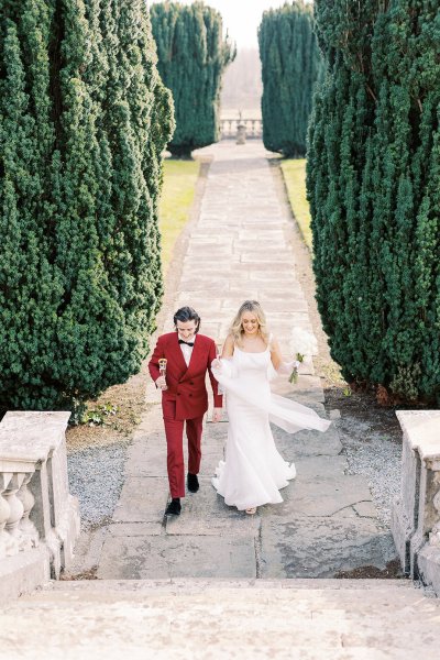 Bride and groom exterior manor venue flowers holding flutes filled with champagne prosecco