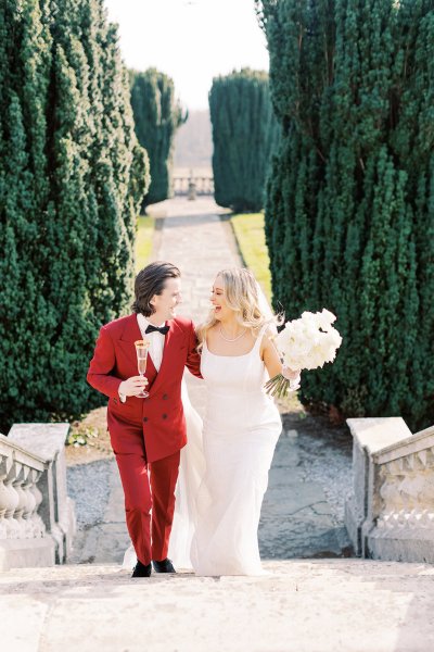 Bride and groom exterior manor venue flowers holding flutes filled with champagne prosecco walking up the steps