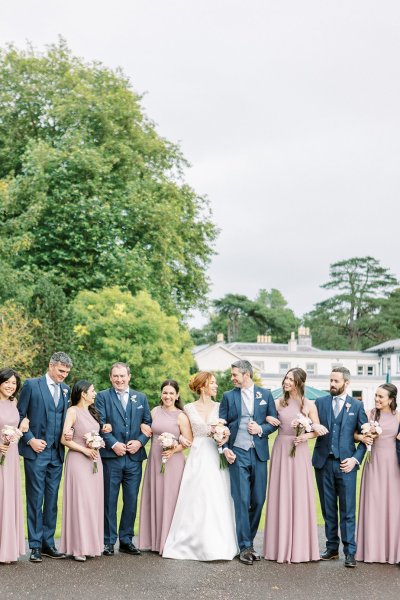 Bride with bridesmaids they are holding white flowers with groom and groomsmen