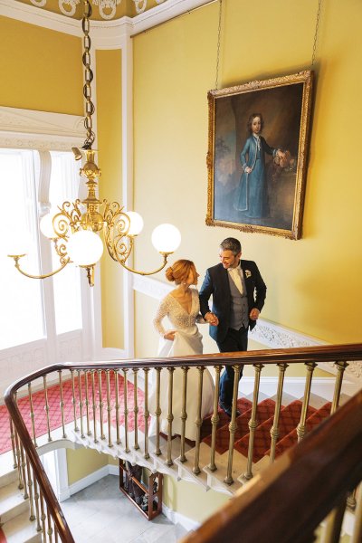 Bride and groom walk down the stairs in venue