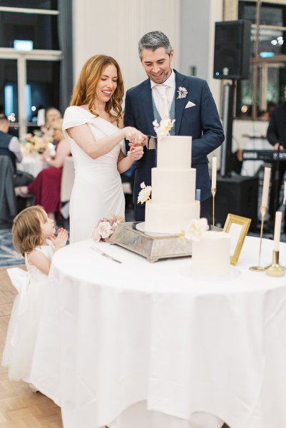 Bride and groom cut the white wedding cake