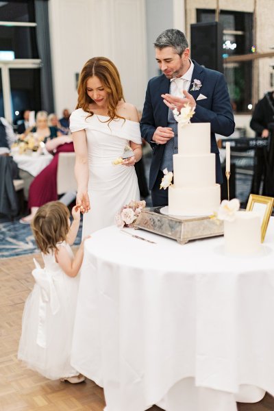 Bride and groom cut the white wedding cake