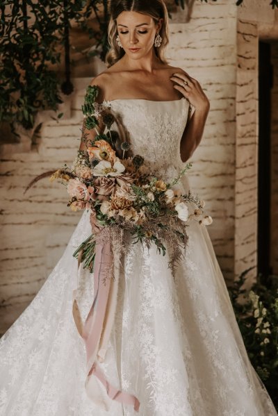 bouquet pastel Bride on her own looking down wearing white bridal gown dress holding bouquet of flowers