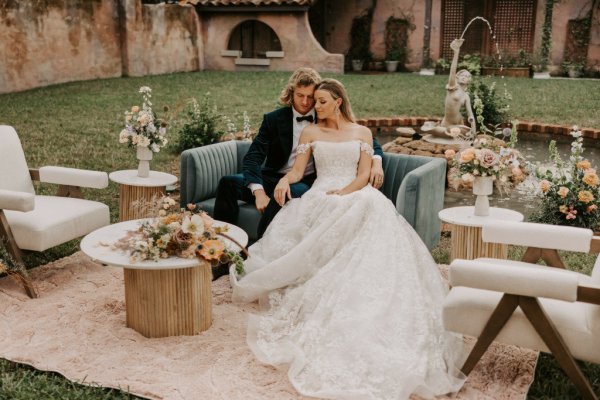 Muted Rainbow Styled Shoot couple holding bouquet of flowers on table sitting on sofa couch chair