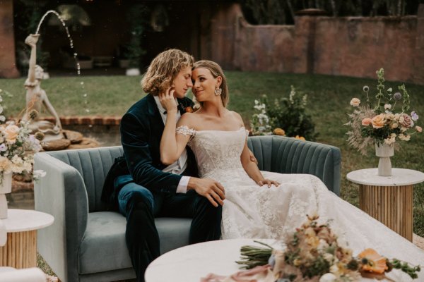 Muted Rainbow Styled Shoot couple holding bouquet of flowers on table over the shoulder kiss