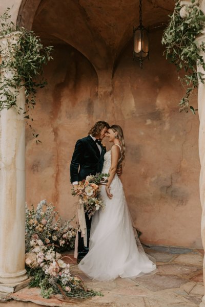 Muted Rainbow Styled Shoot couple holding bouquet of flowers kissing kiss