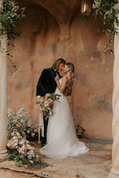 Muted Rainbow Styled Shoot couple holding bouquet of flowers kissing kiss