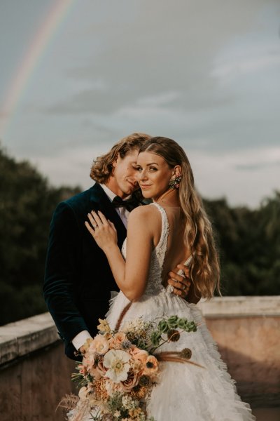 Muted Rainbow Styled Shoot couple holding bouquet of flowers scenic background