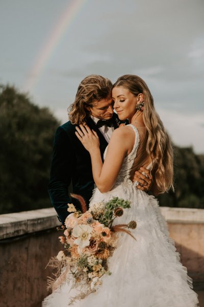 Muted Rainbow Styled Shoot couple holding bouquet of flowers scenic background