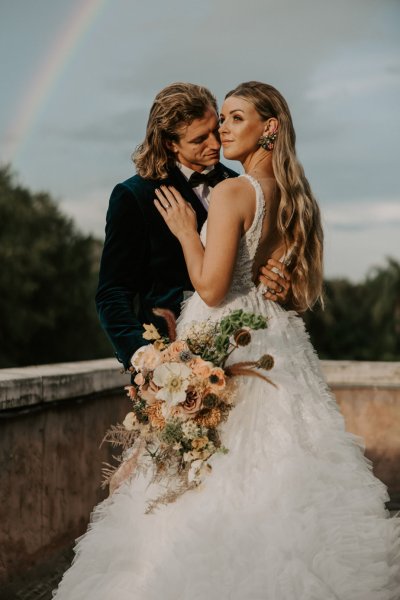 Muted Rainbow Styled Shoot couple holding bouquet of flowers scenic background