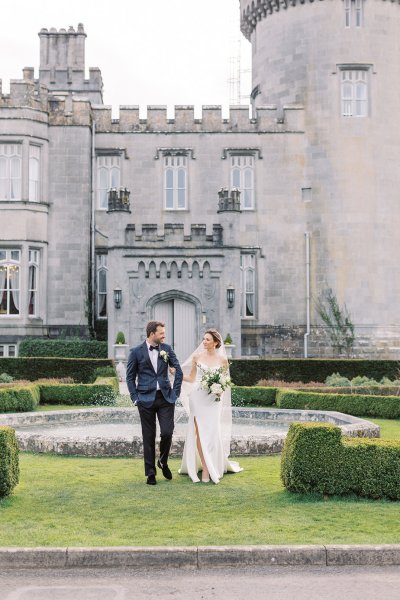 Bride and groom exterior Dromoland Castle in garden holding flowers