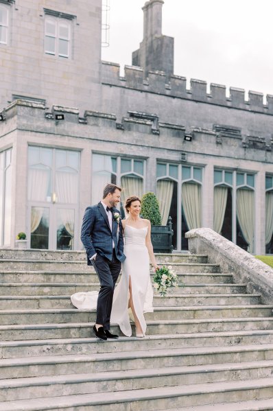 Bride and groom walking down steps exterior castle