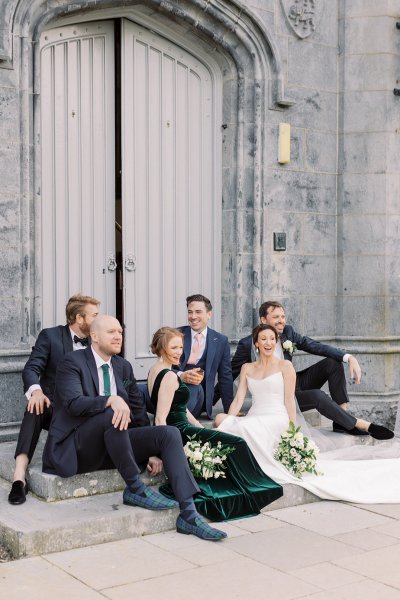 Bride groom and family sitting on steps exterior castle