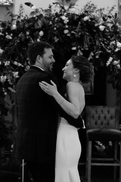 Bride and groom in front of flowers black and white