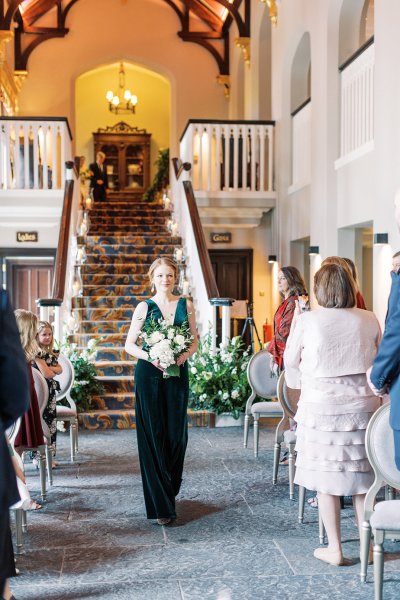 Mother walks down the aisle holding bouquet of flowers