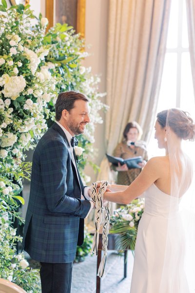 Bride and groom during wedding ceremony beside bed of flowers officiant in background