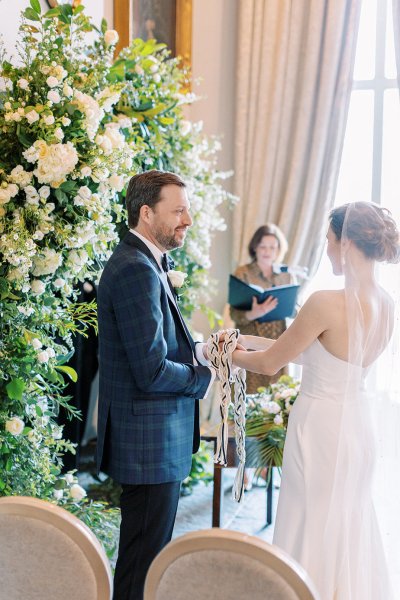 Bride and groom during wedding ceremony beside bed of flowers