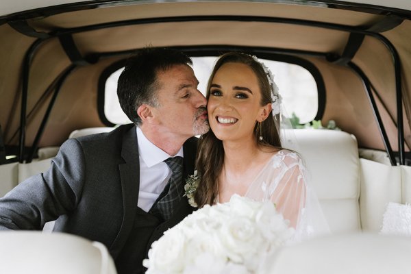 Groom and bride sitting in car white roses flowers wedding