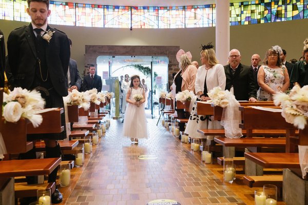 Little flower girl walks down the aisle during wedding