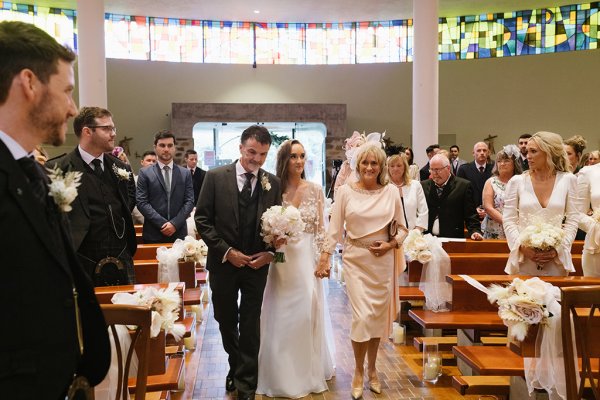 Mother and father walk bride down the aisle during wedding