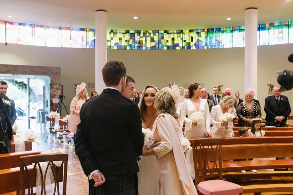 Kiss on the brides cheek mother father and groom at alter