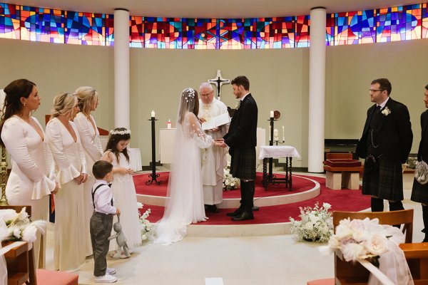 Bride and groom stand at alter with priest during church ceremony