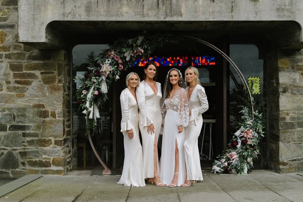 Bridesmaids bride smiling hugging outside of church