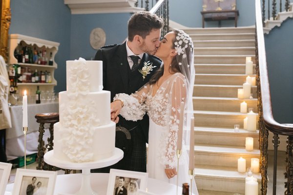 Bride and groom cut the wedding cake lace dress detail