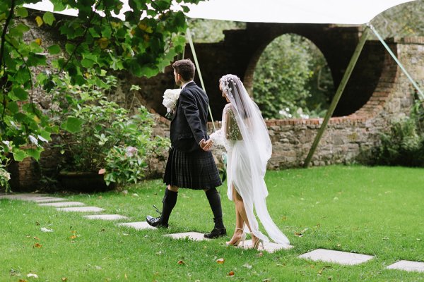 Bride and groom walk in garden