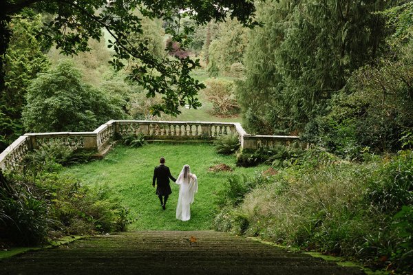 Bride and groom walking in garden lace dress veil detail steps