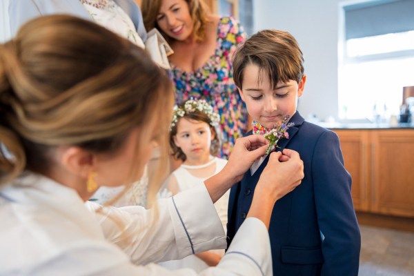 Bride pinning flower detail/accessory on little boys suit jacket