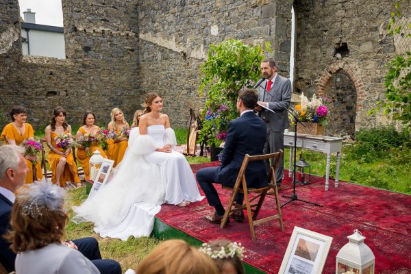 Bride and groom at alter with officiant and guests behind bridesmaids