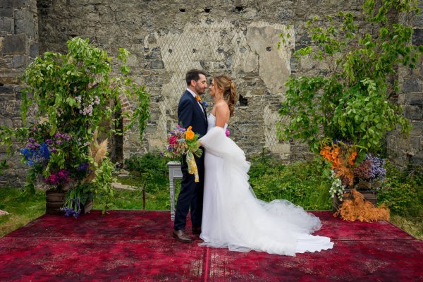 Bride holds bouquet of flowers standing with groom on bed of flowers