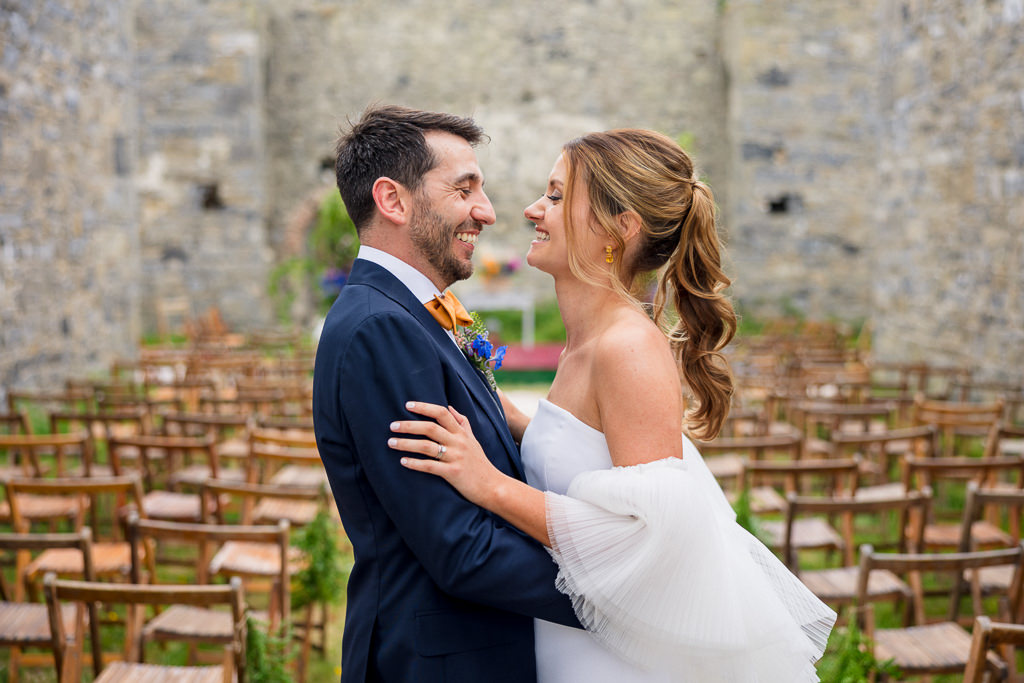 Bride and groom kiss look at each other smiling in front of ceremonial setting