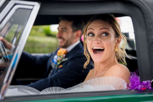 Bride smiles at guests as they pull away in wedding car