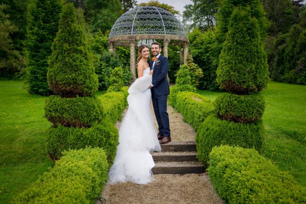 Groom and bride standing on steps facing camera