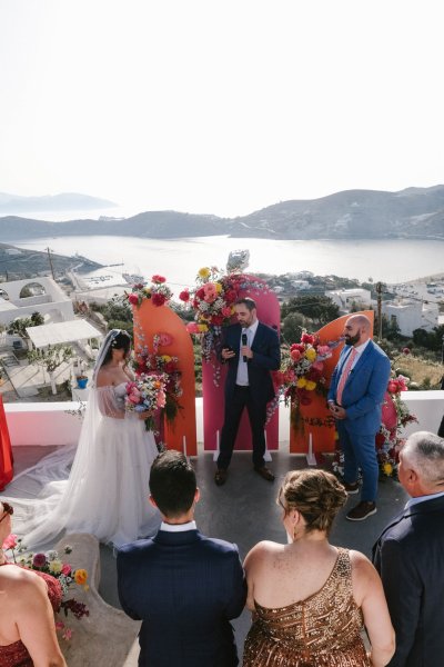 Bride reaches alter top of hotel view sea in background landscape groom guests