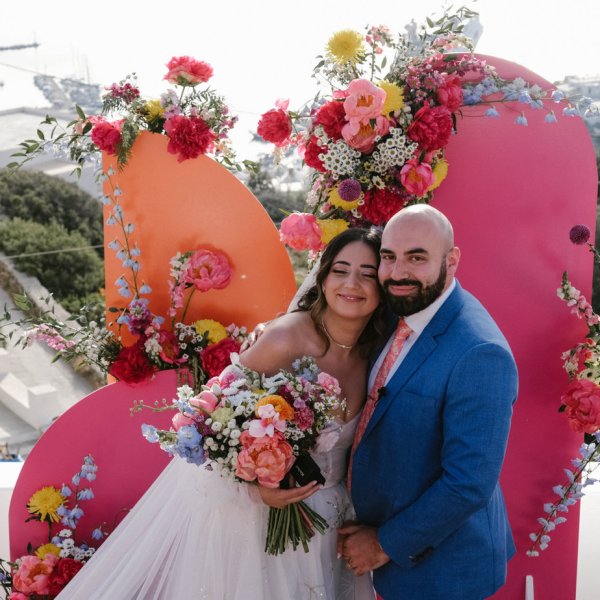 Bride and groom in front of pink setting flowers roses