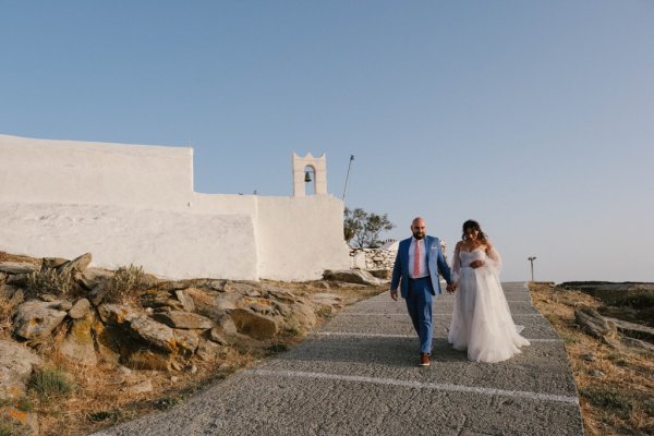 Bride and groom walk hand in hand holding hands in sunshine heat