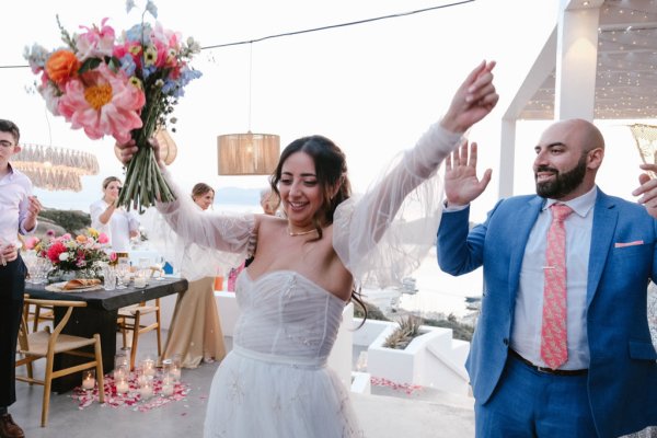 Bride and groom hands in the air bouquet smiling laughing