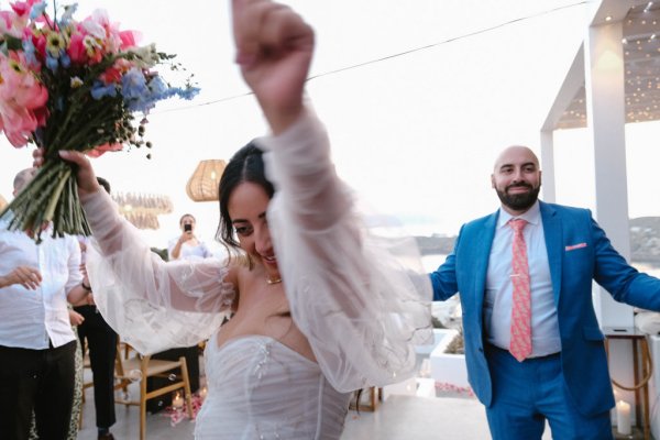 Bride and groom hands in the air bouquet smiling laughing