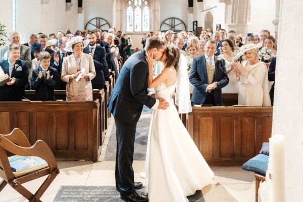 Bride and groom kiss at alter guests clap