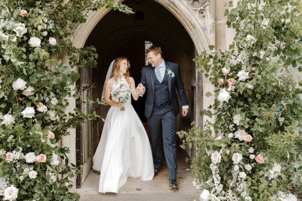 Bride and groom pose at entrance to chapel/church