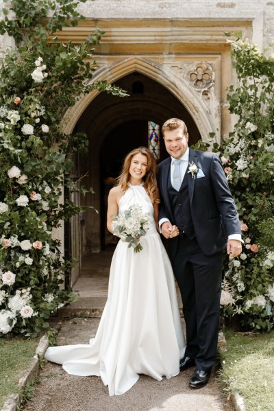 Bride and groom pose at entrance to chapel/church